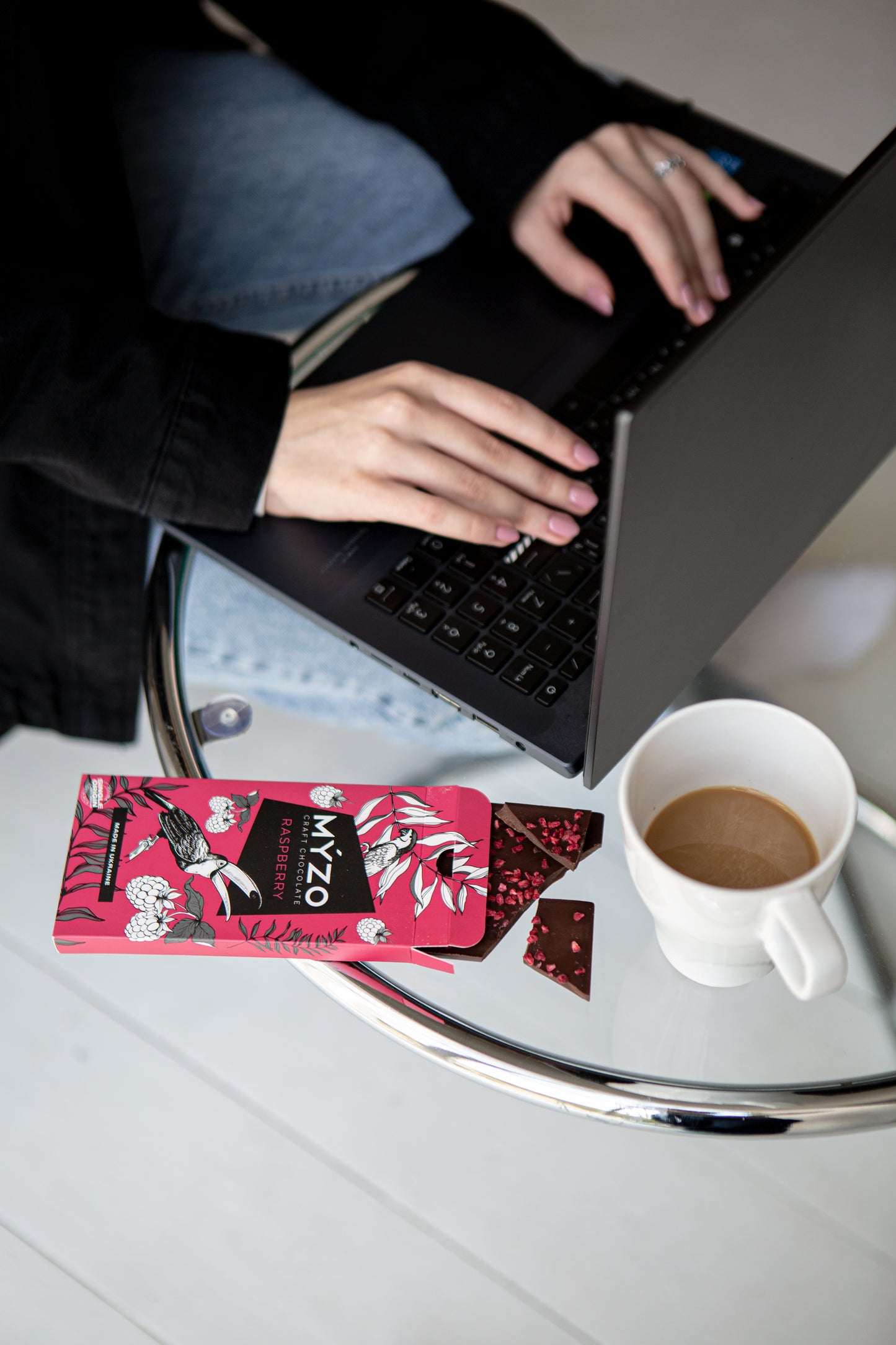 Дівчина працює за компютером з Myzo з малиною та чашкою кави на столі