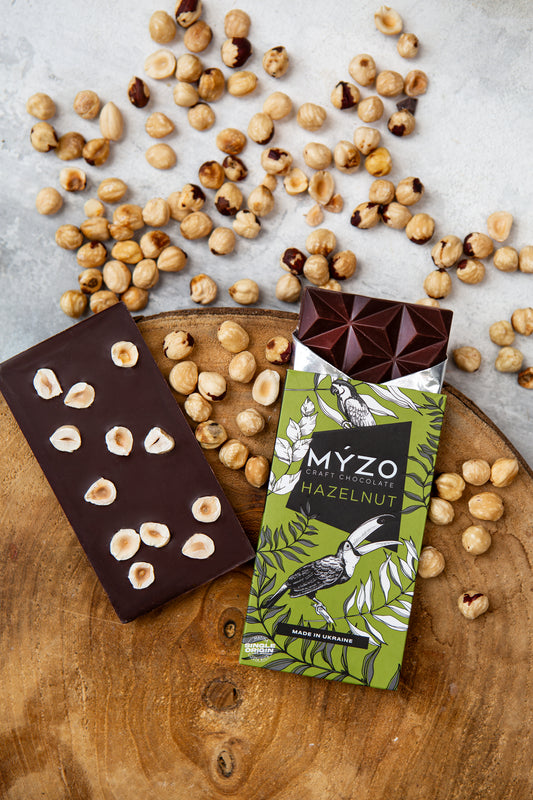 Чорний шоколад з ліщиною Myzo Chocolate на столі з ліщиною навколо