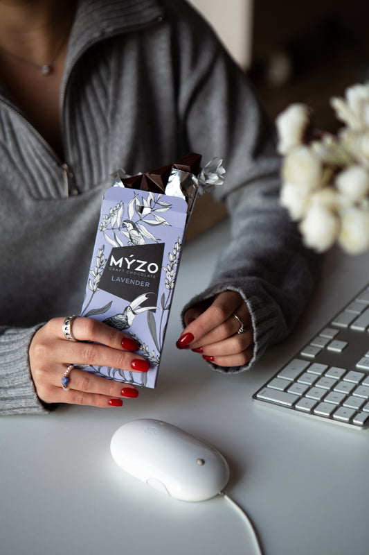 Дівчина їсть Myzo лавандовий шоколад за робочим столом