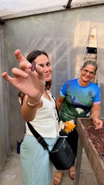 Founder holding a dried cocoa bean at a drying facility