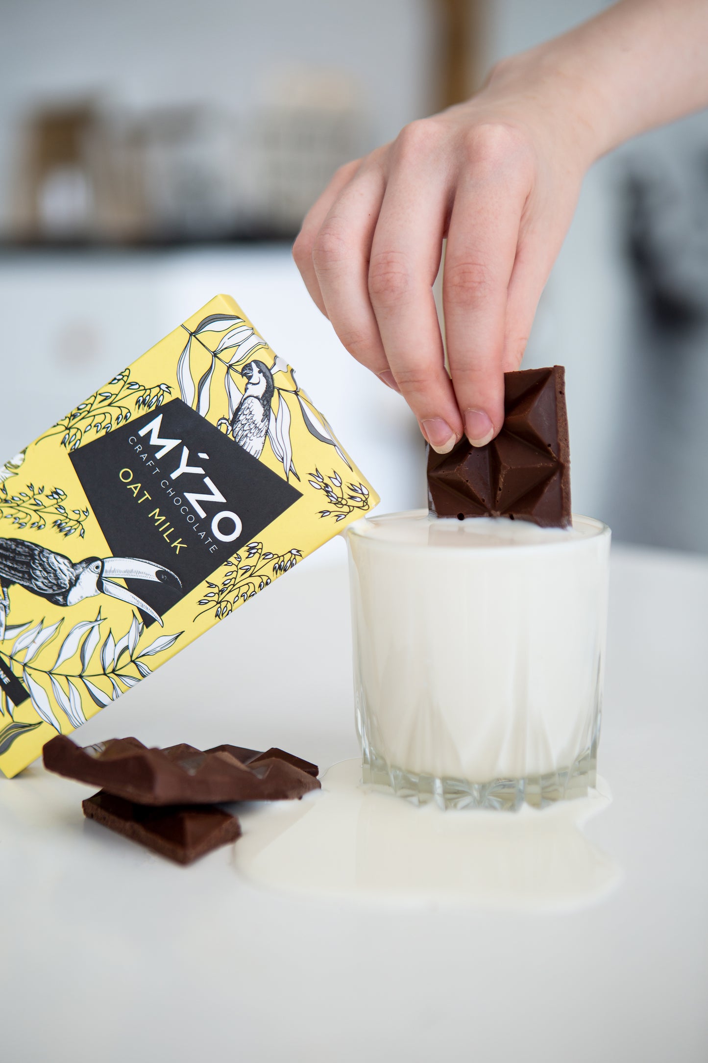 Дівчина мокає Myzo з вівсяним молоком в склянку молока